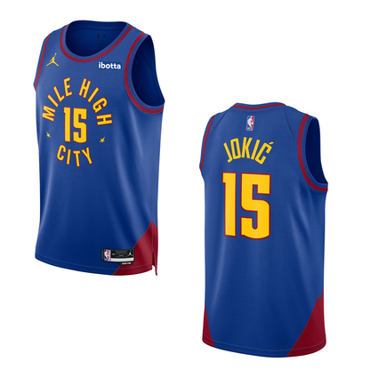 Royal Blue Nuggets Statement Nikola Jokic #15 Swingman Jersey. Has the Mile High City mantra across the chest with the #15 in the middle with yellow lettering surrounding by maroon lining. 