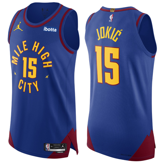 Royal Blue Nuggets Statement Jokic #15 Authentic Jersey. Has the Mile High City mantra across the chest with the #15 in the middle with yellow lettering surrounding by maroon lining. On the back neck tag, has the "1" in gold indicating our one NBA championship.