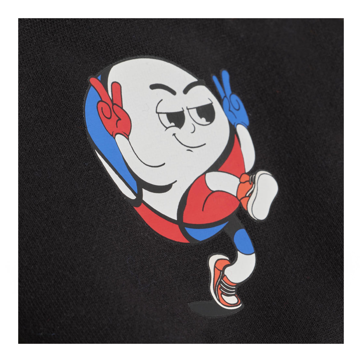 A close-up of a black fabric surface featuring a colorful cartoon graphic of a basketball character wearing red, blue, white, and orange sneakers, making peace signs with both hands.